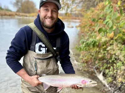 A fisherman holds a rainbow trout.