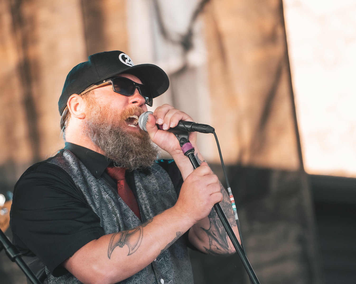 A performer grips a microphone and its stand while singing.