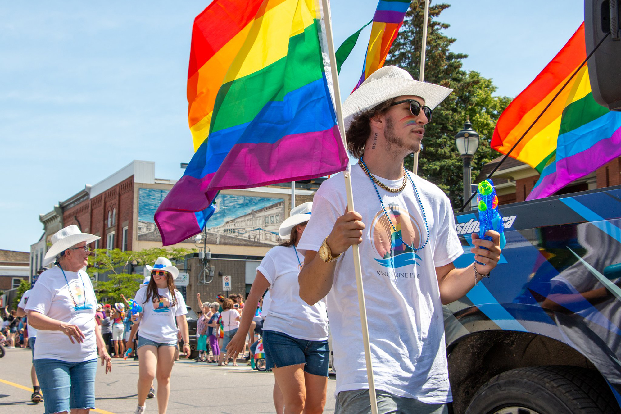 Participants in a Pride Parade march down Queen Street in Kincardine under bright blue skies.